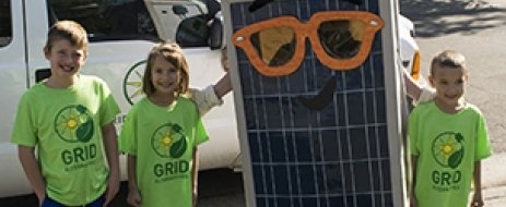 Three children pose with Sunny the Solar Panel