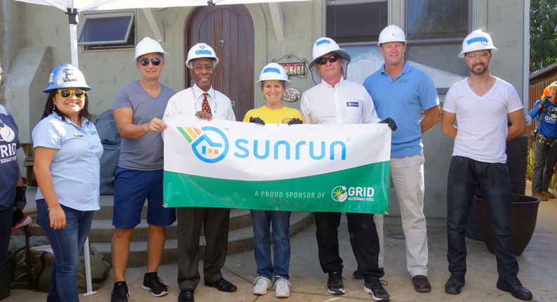 Sunrun employees pose with clients and GRID staff in front of a completed installation