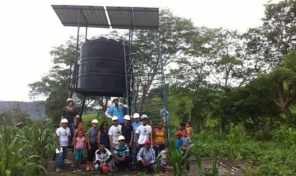 Family and GRID staff around solar-powered irrigation system