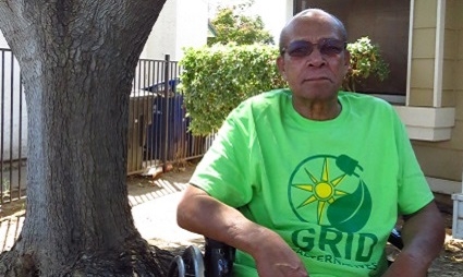 Milton Currie, in a GRID t-shirt, sits in front of his home