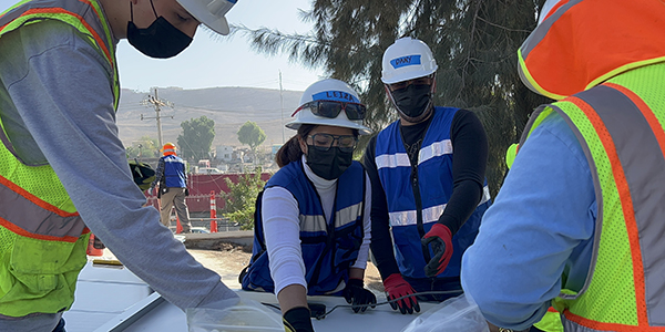 Trainees work on connecting the electrical system to a panel