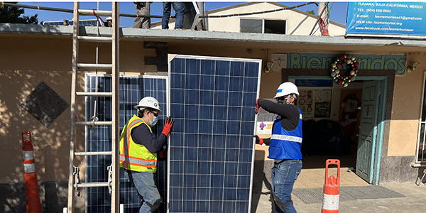 Two women prepare a solar panel to be lifted on the roof