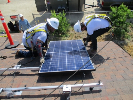 Trainees lay panels on a mock roof