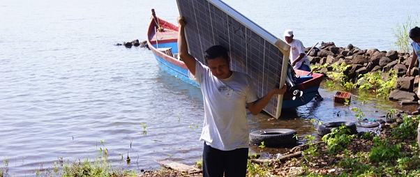Carrying a solar panel on his back, an installer walks away from the boat that brought him to San Fernando Island