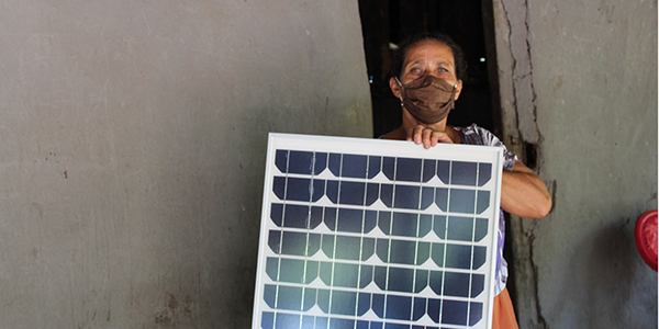Masked Nicaraguan woman holding a solar panel
