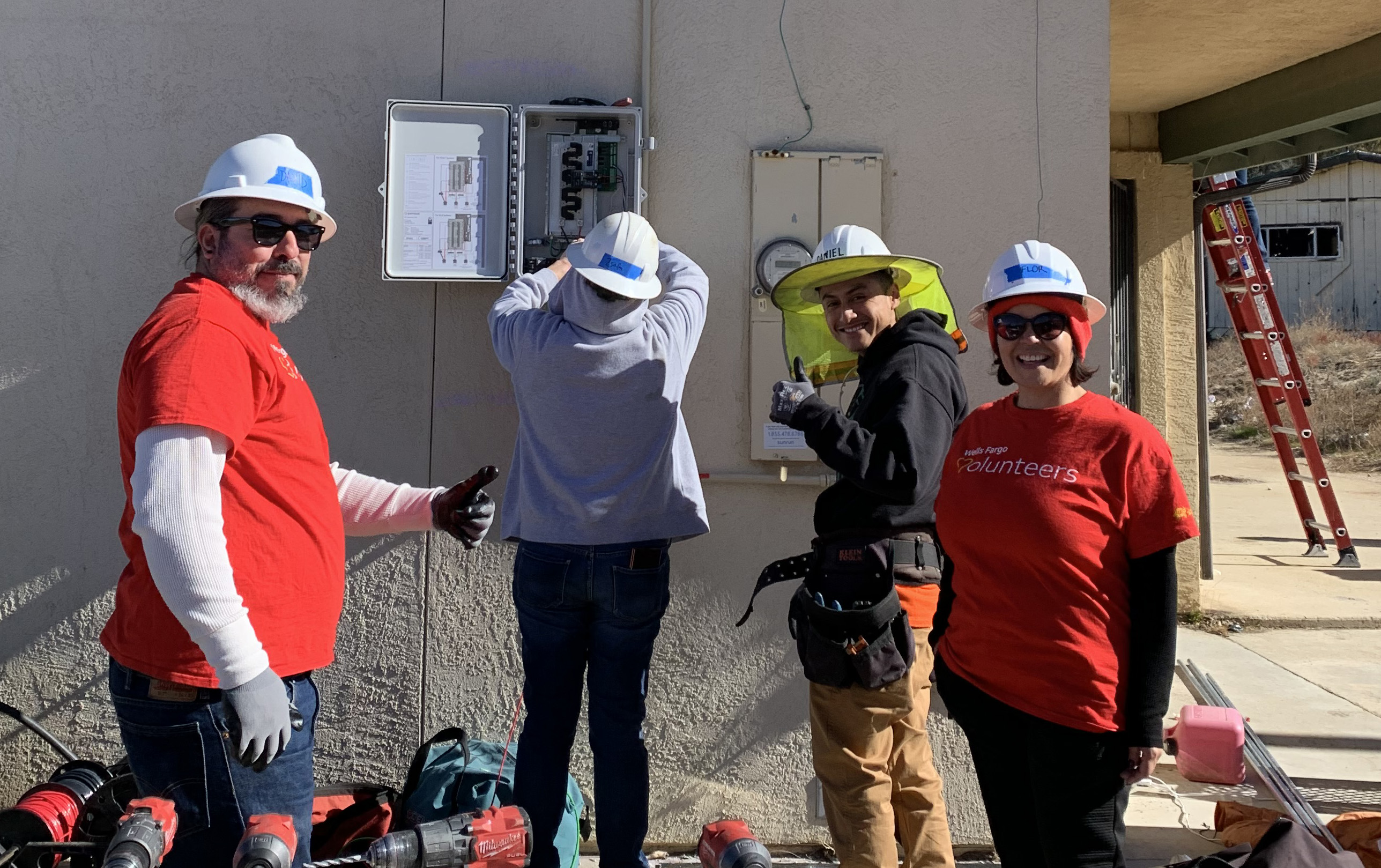 Volunteers learning how to wire the combiner box with Danny, a GRID IE Solar Installation Supervisor