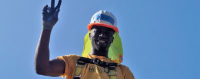 Marvin, a Solar Works DC trainee, waves from the roof during a solar installation.