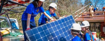 Women pull a solar panel off of a truck