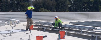 Two people on a rooftop working on a solar panel 