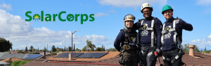 3 people smiling on the roof with the solarcorps logo