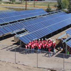 An enormous community solar field with a group of Wells Fargo volunteers in front
