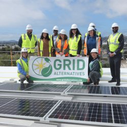 GRID Bay Area and Department of Energy staff a GRID Alternatives banner in front of solar panels
