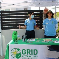 Two GRID Alternatives staff members stand while they table