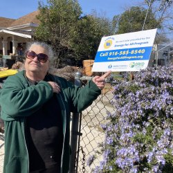 Stockton resident and GRID client Patricia Barret in front of Energy for All lawn sign