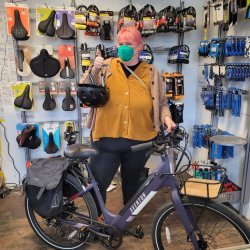 An Electric Bike program beneficiary stands next to her new E-bike at the Watershed Workshop, a community based organization that has partnered up with GRID Alternatives Bay Area's Clean Mobility Program