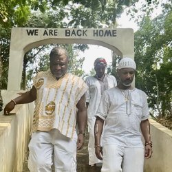 GRID Mid-Atlantic Warehouse and Facilities Manager Sundiata Ramin (right) walks under an archway that reads "We Are Back Home" while visiting Ghana in January 2024.