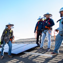 four men installing solar on a roof top