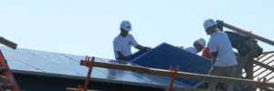 Installers lay a module on a roof with a steep rake