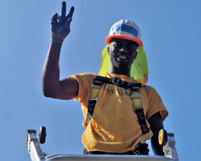 Marvin, a Solar Works DC trainee, waves from the roof during a solar installation.