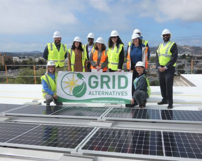 GRID Bay Area and Department of Energy staff a GRID Alternatives banner in front of solar panels