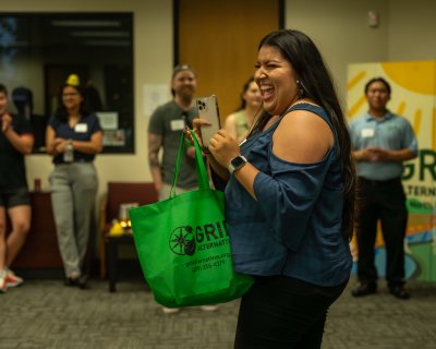 Sophia from Rising Sun Center for Opportunity smiling after winning a green GRID swag bag in a raffle.