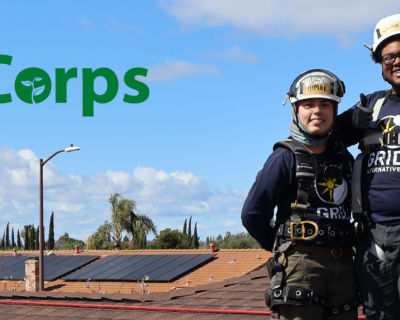 3 people smiling on the roof with the solarcorps logo