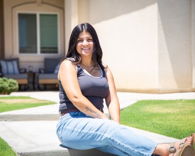 Woman sitting down in front of her home