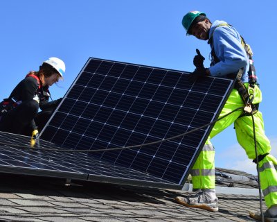 A volunteer and GRID staff member install solar on a roof
