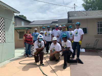 Ms. Audrey in her backyard with the GRID staff and solar job trainees who installed solar on her home..