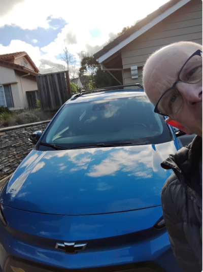 Clean Cars For All program beneficiary stand next to his new GM EV Bolt