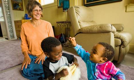 Adult woman with two young children playing together in a living room