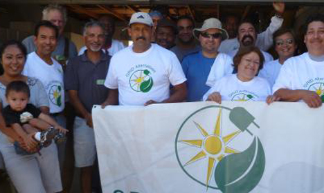 Group holding banner with sun and leaf logo at community event in Piru, CA
