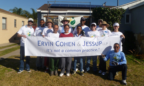 Group of volunteers holding Ervin Cohen & Jessup banner during outdoor community workday