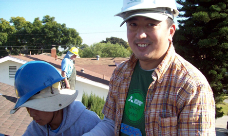 Two workers installing solar panels on a residential roof on a sunny day