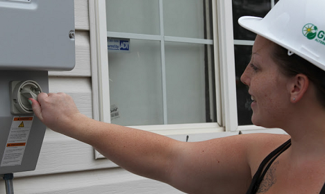 Worker in hard hat adjusting thermostat on exterior wall