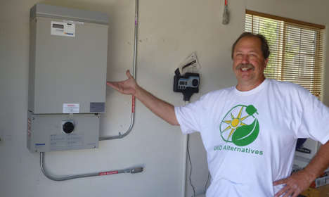 Man in eco alternatives shirt gestures toward wall-mounted heating unit in home installation setting