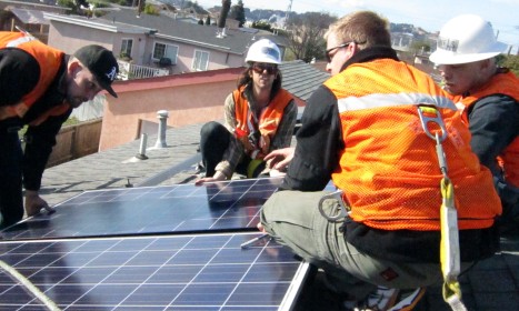 Workers in safety gear installing solar panels on a residential rooftop