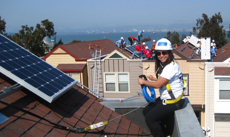 Worker in safety gear installing solar panels on residential roofing