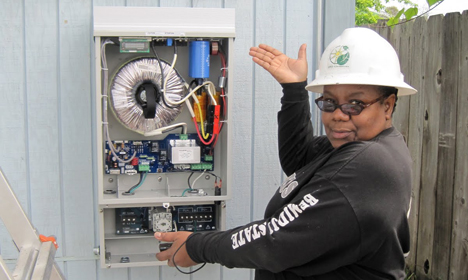 Technician in hard hat and safety glasses installing solar inverter equipment on white wall panel