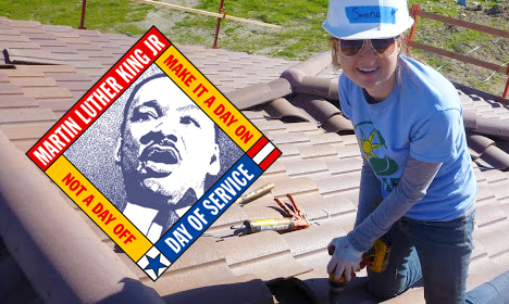 Person in blue shirt and white cap holding MLK Day of Service sign with Martin Luther King Jr. portrait and text "A day on, not a day off