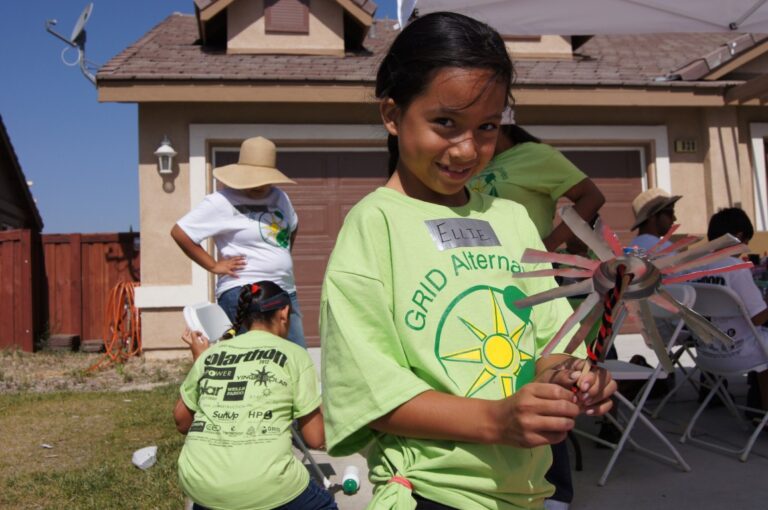 Girl holding pinwheel at GRID Alternatives community solar event in residential neighborhood