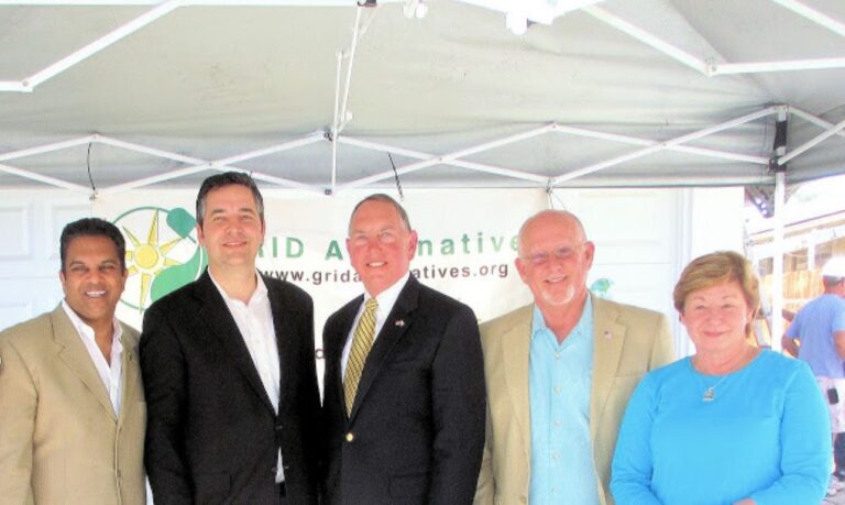Five people posing under tent with GRID Alternatives logo at Earth Day 2013 event