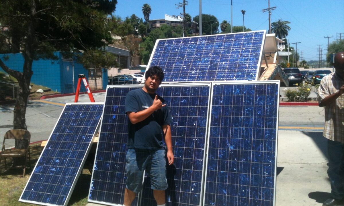 Man standing among solar panels displays renewable energy training program for community members