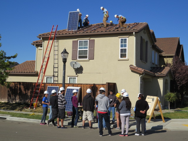 Woodland students install solar panels on house roof during educational demonstration