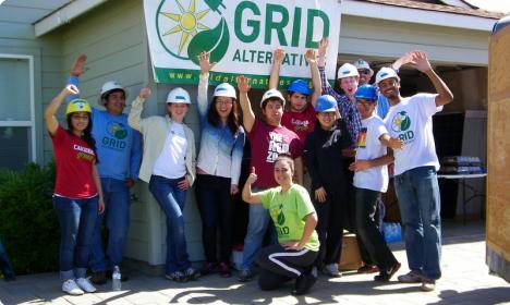 Group of students in hard hats posing in front of GRID Alternatives banner at construction site