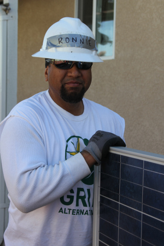 Worker installing solar panel wearing white hard hat and Renewable Alternatives shirt