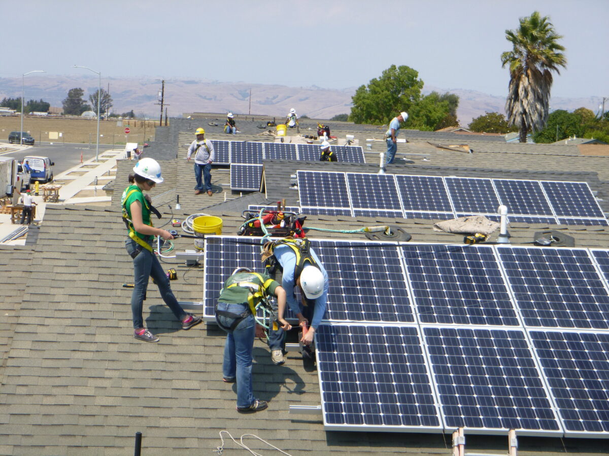 Workers installing solar panels on a residential roof during Solarthon 2014