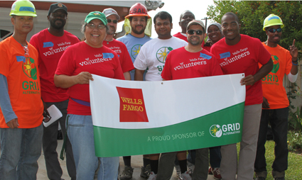Group of volunteers in hard hats holding Wells Fargo and GRID banner at outdoor event