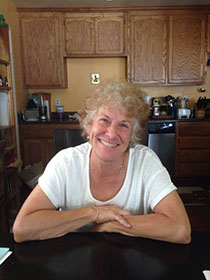 Woman smiling at kitchen counter with wooden cabinets in background