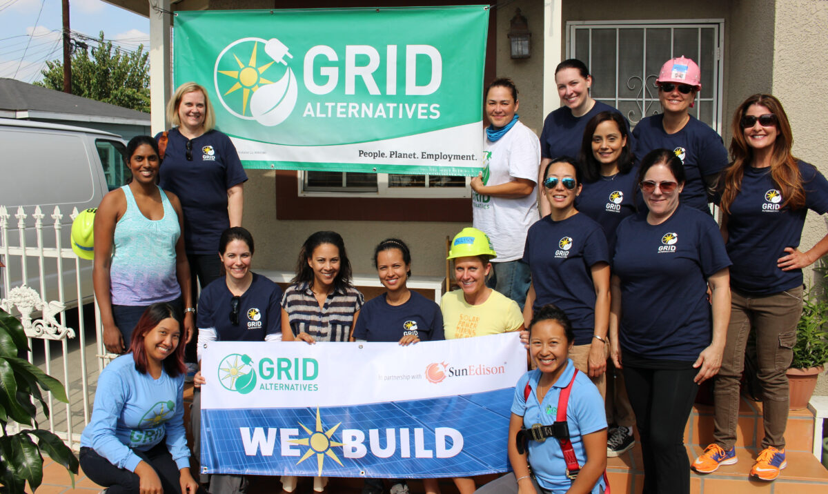 Group of volunteers holding "We Build" banner at GRID Alternatives community solar installation event